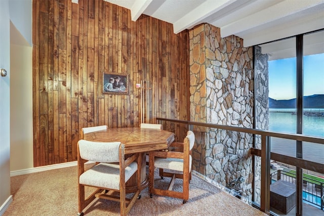 dining room featuring beam ceiling, wooden walls, carpet floors, and a mountain view