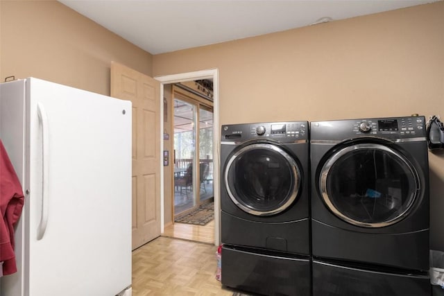 clothes washing area with washing machine and dryer and light parquet floors