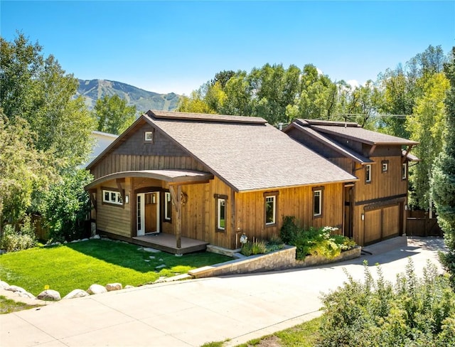 view of front of house featuring a mountain view, covered porch, a front yard, and a garage