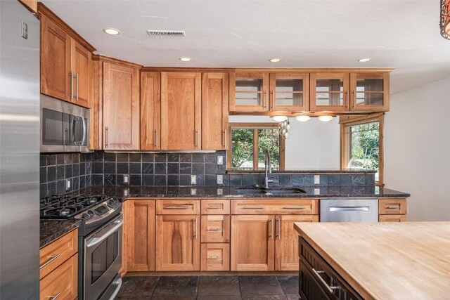 kitchen featuring dark stone countertops, sink, appliances with stainless steel finishes, and tasteful backsplash