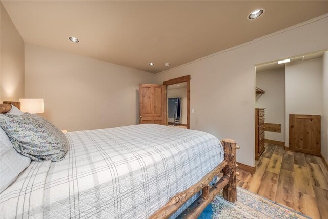 bedroom with light hardwood / wood-style floors and a walk in closet