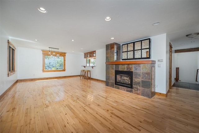 unfurnished living room featuring light wood-type flooring and a tiled fireplace