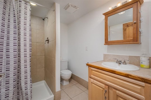 bathroom featuring tile patterned flooring, vanity, toilet, and tiled shower