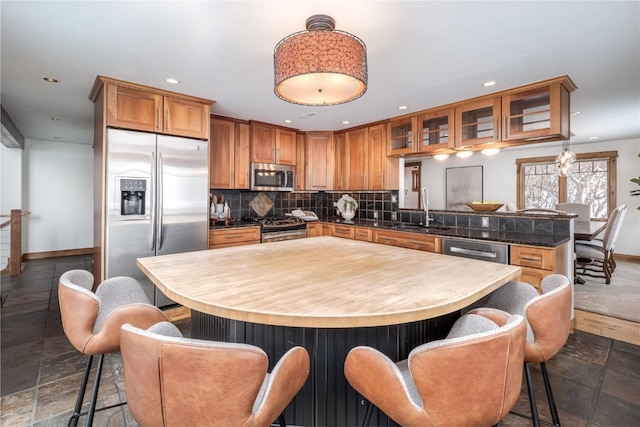 kitchen featuring decorative backsplash, appliances with stainless steel finishes, kitchen peninsula, a kitchen breakfast bar, and sink