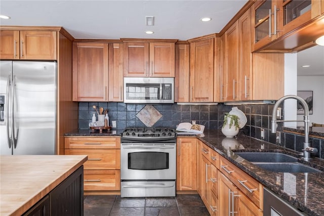 kitchen featuring backsplash, sink, stainless steel appliances, and wooden counters