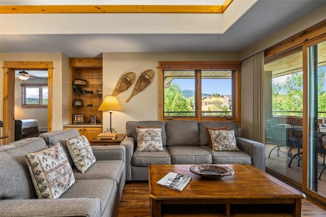 living room featuring ceiling fan, built in shelves, and dark hardwood / wood-style flooring