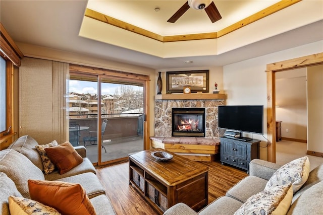 living room with ceiling fan, hardwood / wood-style flooring, a fireplace, and a tray ceiling