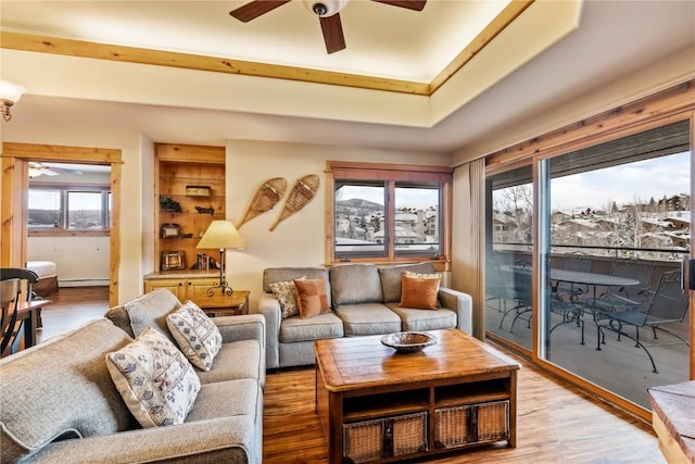 living room featuring wood-type flooring, baseboard heating, and ceiling fan