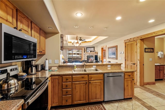 kitchen featuring light tile patterned floors, sink, a raised ceiling, kitchen peninsula, and stainless steel appliances