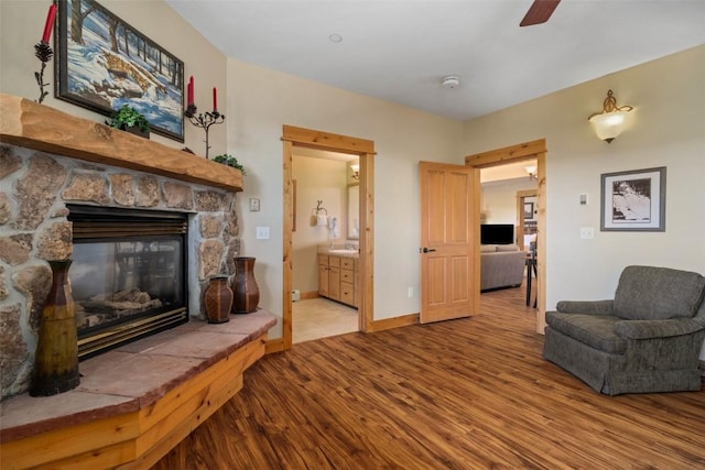 living area with a fireplace, light hardwood / wood-style floors, and ceiling fan