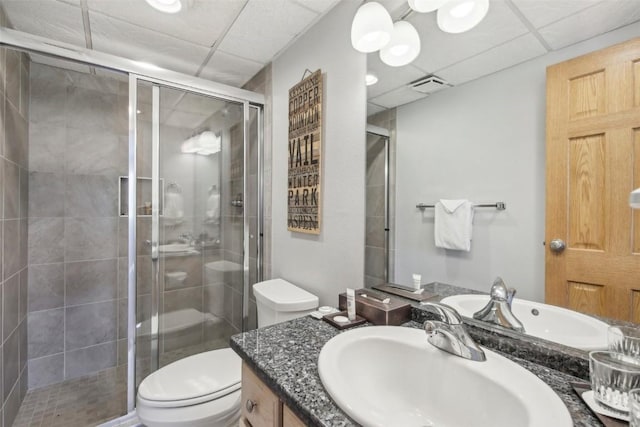 bathroom featuring a paneled ceiling, vanity, toilet, and a shower with door