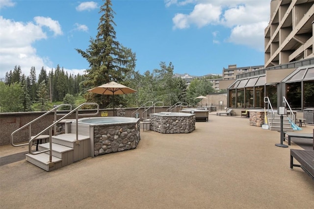 view of patio featuring a sunroom, a jacuzzi, and an outdoor fire pit