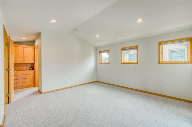 empty room with light carpet, recessed lighting, baseboards, and vaulted ceiling