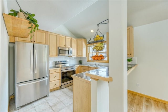 kitchen featuring light brown cabinetry, lofted ceiling, decorative backsplash, a peninsula, and stainless steel appliances