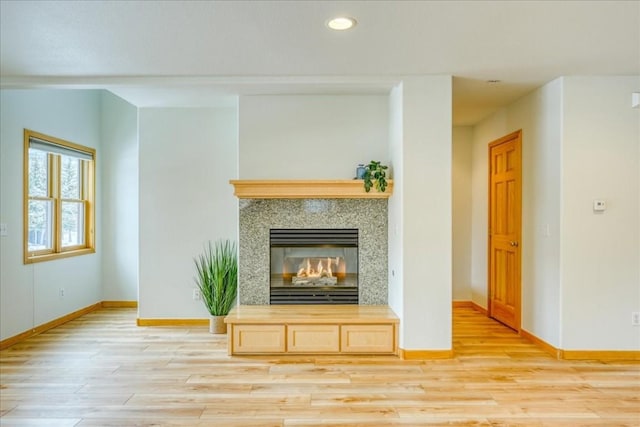 unfurnished living room featuring a multi sided fireplace, recessed lighting, baseboards, and light wood-style floors