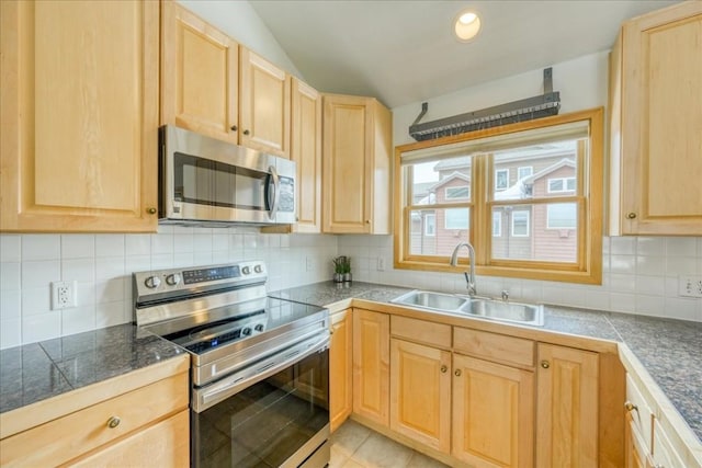 kitchen with a sink, tile counters, appliances with stainless steel finishes, and light brown cabinetry