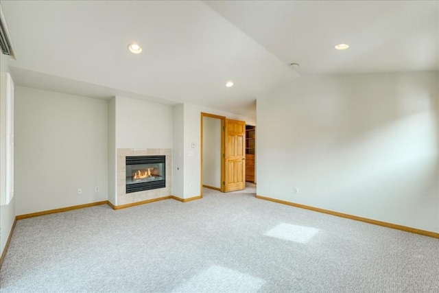 unfurnished living room featuring baseboards, light carpet, a fireplace, and vaulted ceiling