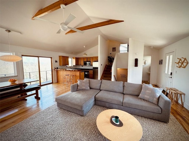 living room with high vaulted ceiling, ceiling fan, and light hardwood / wood-style flooring