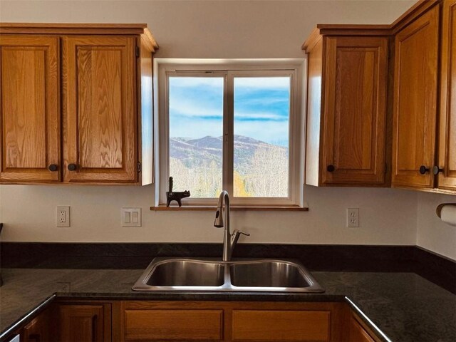 kitchen featuring a mountain view, sink, and dark stone counters