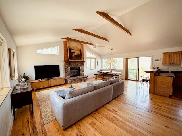 living room featuring high vaulted ceiling, a stone fireplace, light hardwood / wood-style floors, and ceiling fan