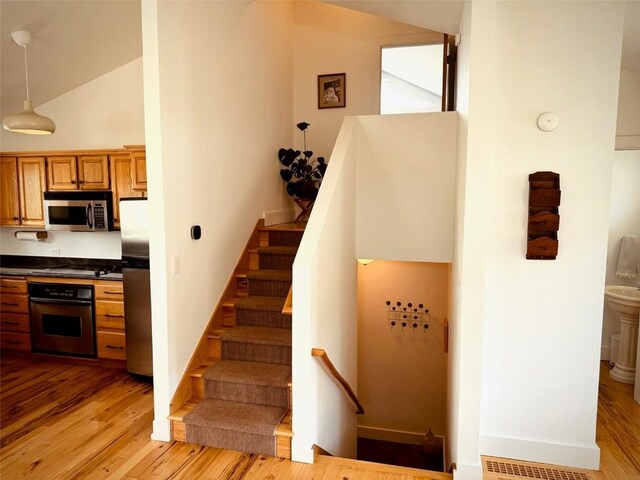 stairs featuring high vaulted ceiling and hardwood / wood-style floors