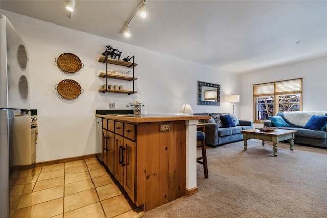 living area with light tile patterned floors, rail lighting, light colored carpet, and bar