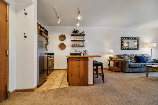 kitchen with light carpet, appliances with stainless steel finishes, open floor plan, a kitchen bar, and open shelves