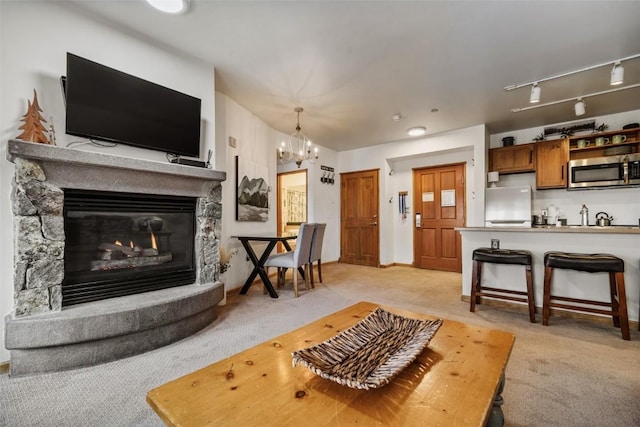 living room with a glass covered fireplace, light carpet, a notable chandelier, and track lighting