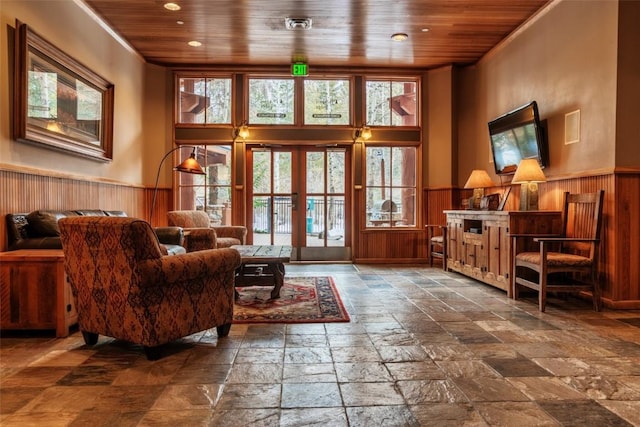 living area with wood ceiling, wainscoting, and stone tile floors