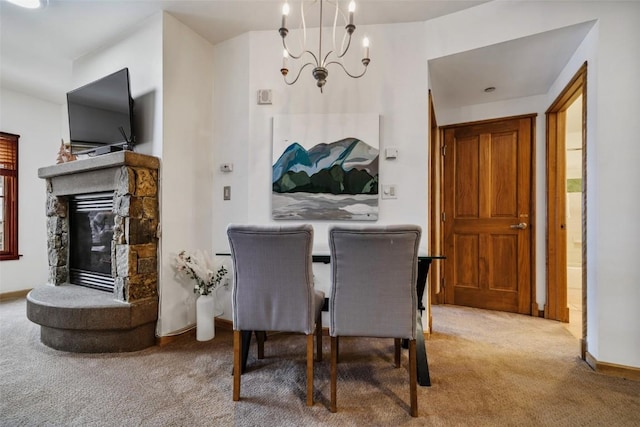 carpeted dining room with a notable chandelier, a stone fireplace, and baseboards