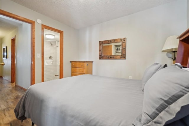 bedroom featuring connected bathroom, a textured ceiling, and wood finished floors