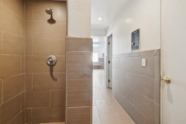 full bath featuring tiled shower and tile walls