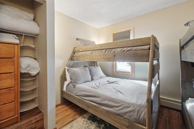 bedroom featuring a textured ceiling, baseboards, and wood finished floors