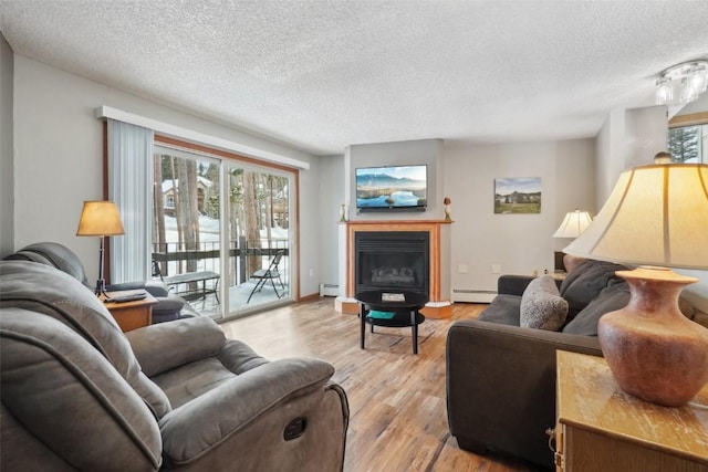 living room featuring a baseboard heating unit, a fireplace, a wealth of natural light, and light wood-style floors