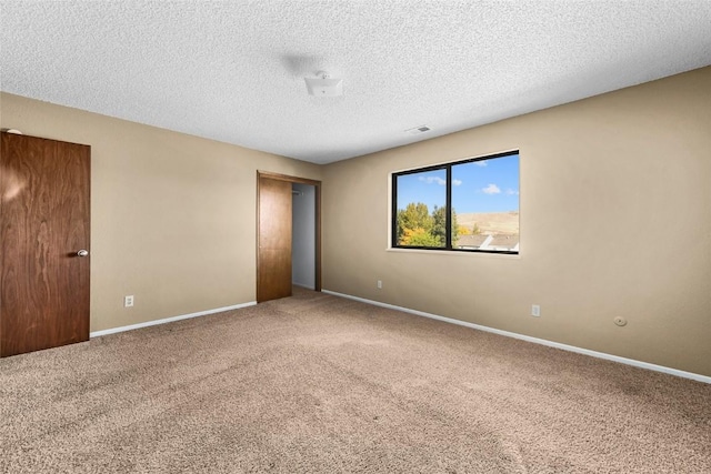 unfurnished room with baseboards, a textured ceiling, visible vents, and carpet flooring