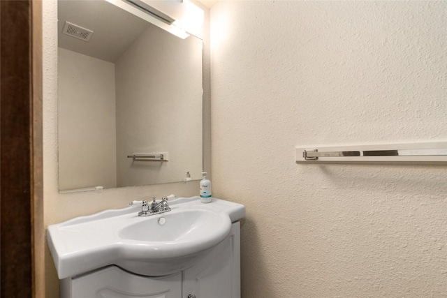 bathroom featuring a textured wall, visible vents, and vanity