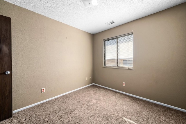 carpeted spare room featuring visible vents, a textured wall, a textured ceiling, and baseboards