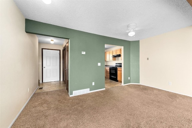 interior space with a textured ceiling, baseboards, visible vents, and light colored carpet