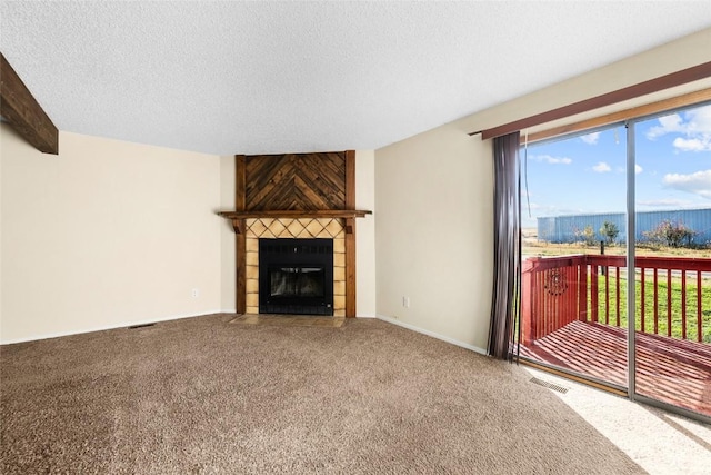 carpeted living area featuring baseboards, visible vents, a textured ceiling, a fireplace, and beam ceiling