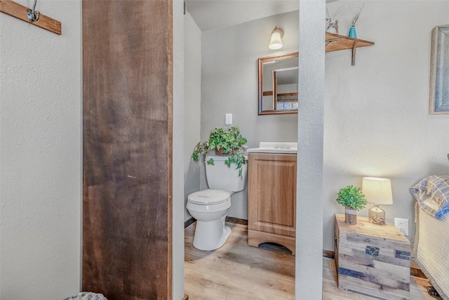 bathroom featuring vanity, wood finished floors, toilet, and baseboards