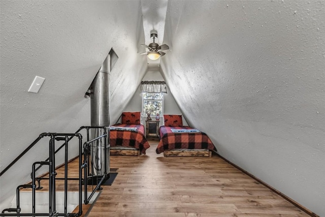 bonus room with vaulted ceiling, a textured ceiling, wood finished floors, and a ceiling fan