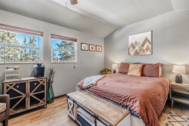 bedroom with vaulted ceiling, light wood-style flooring, and ceiling fan