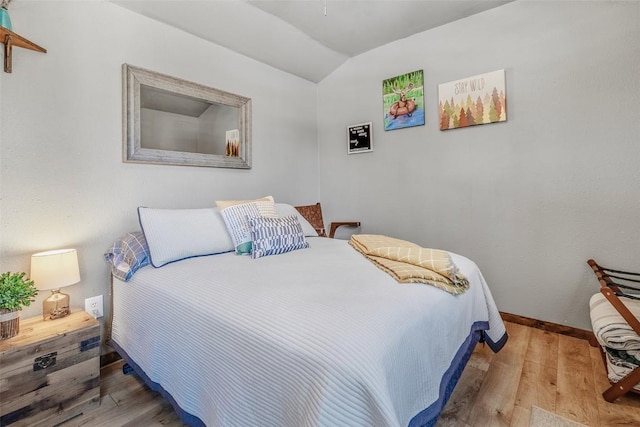 bedroom featuring lofted ceiling, baseboards, and wood finished floors