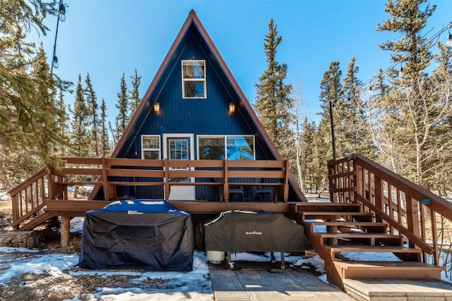 snow covered back of property featuring a deck and stairway