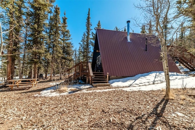 view of snow covered exterior featuring metal roof and stairway