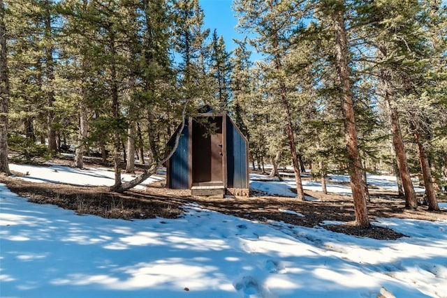 snowy yard with a storage unit and an outdoor structure