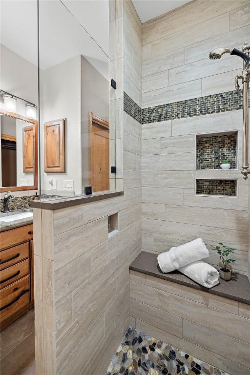 bathroom featuring a tile shower and vanity