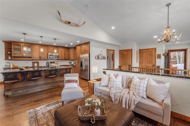 living room featuring baseboards, wood finished floors, high vaulted ceiling, a notable chandelier, and recessed lighting