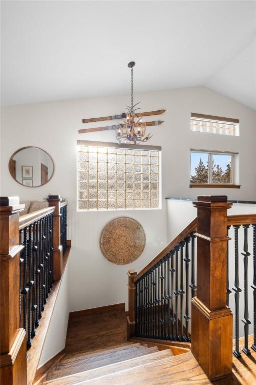 stairway featuring a chandelier, vaulted ceiling, and wood finished floors