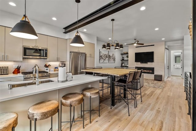 kitchen with hanging light fixtures, high end appliances, a breakfast bar area, and light wood-type flooring